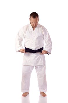 Man in karate-gi fastening his black belt