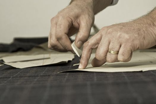 Tailor at work, drawing line on fabric with chalk