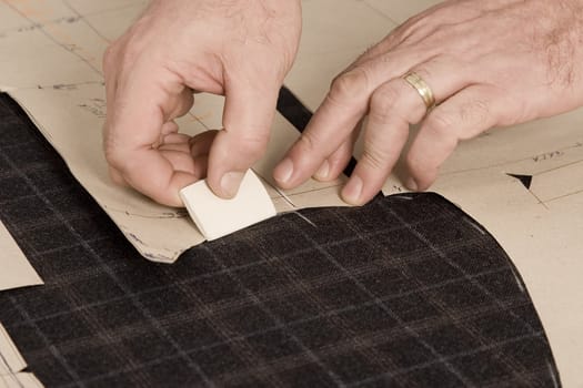 Tailor at work, drawing line on fabric with chalk