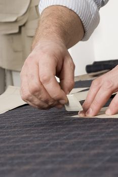 Tailor at work, drawing line on fabric with chalk