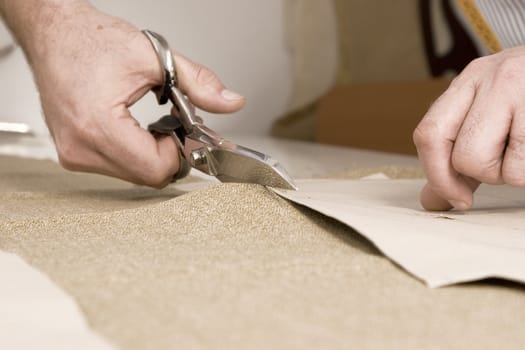 Tailor working at studio cutting fabric, detail of hand with scissors