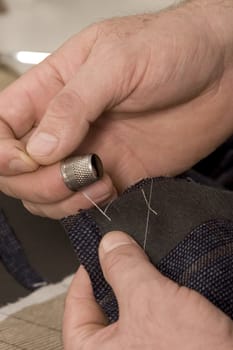 detail of sewing hand in tailor studio