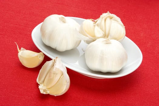 garlic in white bowl over red fabric background