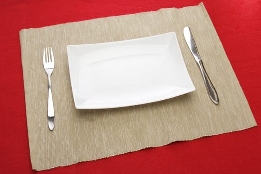 white plate fork and knife on red table