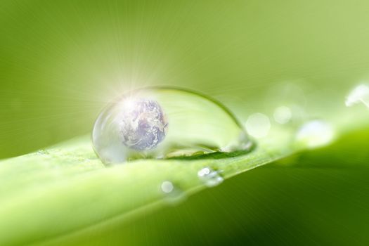 Planet earth inside a drop of dew and sunlight effect