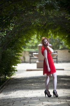 WOman in red dress under vivid green foliage arches