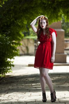 WOman in red dress under vivid green foliage arches