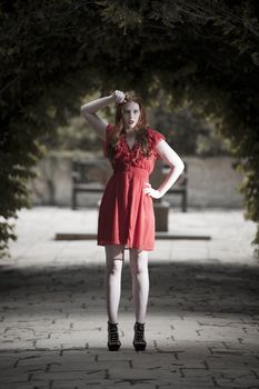 Young woman in red dress in subdued light and gothic looking