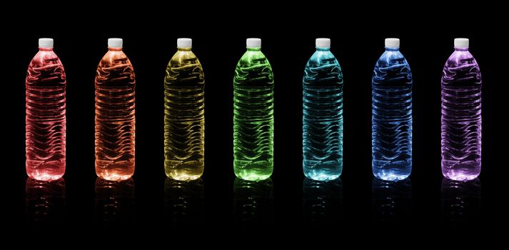 Seven bottles of drinking water colors of the rainbow on a black background