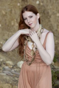 A young woman with beautiful milky skin and red hair wearing Bohemian jewellery
