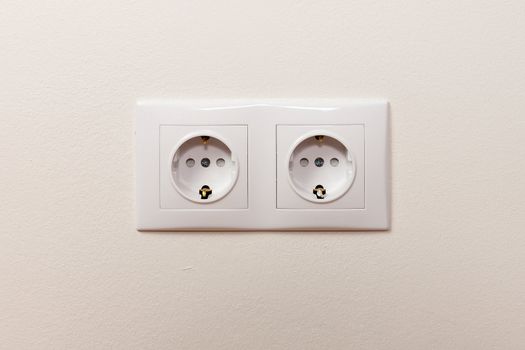 White electric socket on the wall. Close up.