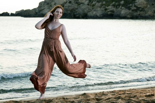 A young female model and dancer jumps and dances on a Mediterranean beach