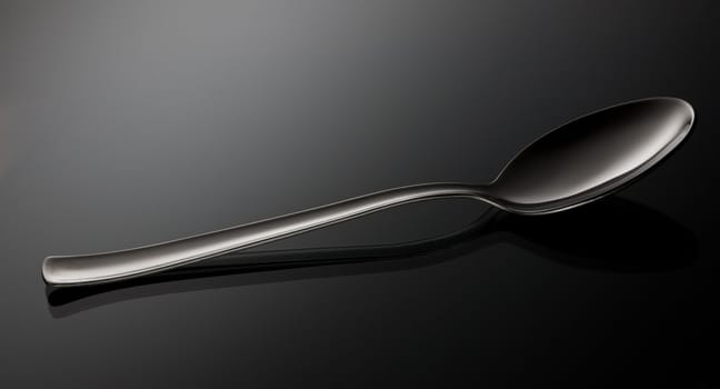 empty shiny silver spoon  on black reflective surface