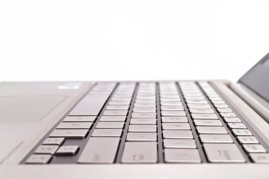 Angled view of a keyboardpad on a modern metal-finished laptop against white for abstract and background