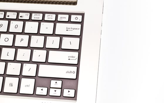 Angled view of a keyboardpad on a modern metal-finished laptop against white for abstract and background