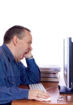 Tired man yawning at his computer keyboard