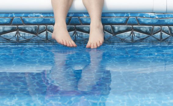 a young kids feet over blue pool water