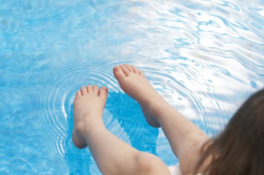 a young kids feet over blue pool water
