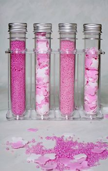 Four bottles with pink salt for baths in a transparent support