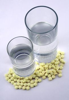 Many yellow tablets and two glasses with water
