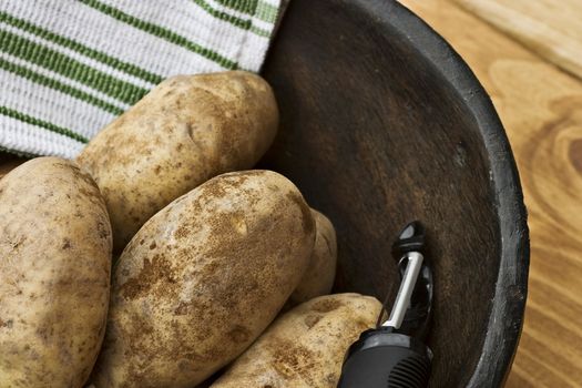 Potatoes in a hand carved wooden bowl with kitchen towel.