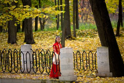 lady in medieval red dress in the autumn forest
