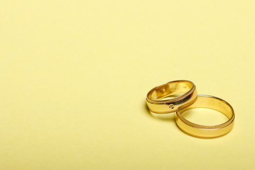 Pair of wedding bands isolated on yellow background, macro