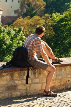 man sitting on a background of green foliage in Prague