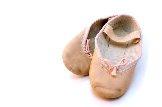 Small pink ballet shoes resting on a white background