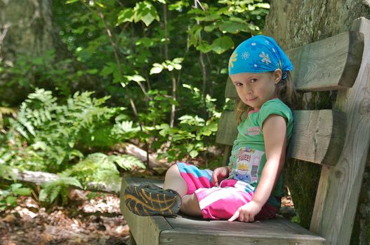 Cute little girl taking a break on a park in the forest
