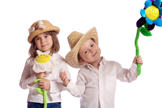 Cute little brother and sister playing with hats and flowers