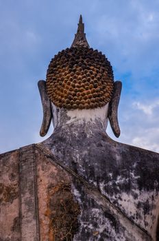 Detail of head of stone statue of sitting Buddha in Sukhothai historical park, Thailand