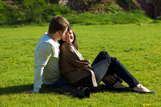 young couple sitting on the green grass