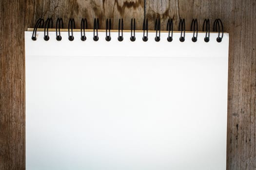 white notebook on the wood backgroung with pink flower