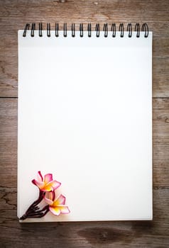 white notebook on the wood backgroung with pink flower