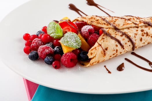 fresh tasty homemade crepe pancake with chocolate sauce fruits and berries
