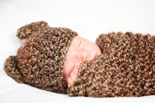 Newborn baby boy resting in a wool cocoon