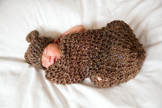 Newborn baby boy resting in a wool cocoon