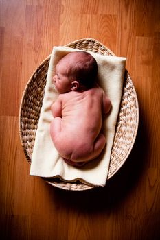 Naked newborn baby boy resting in a wicker basket