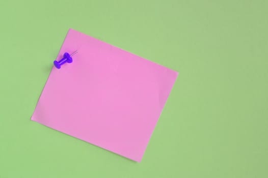 pink note paper with pin on green background