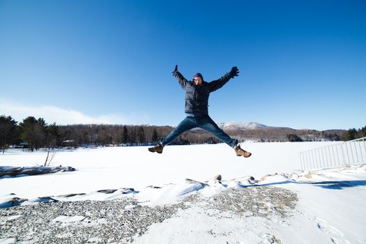 Man jumping by a frozen lake