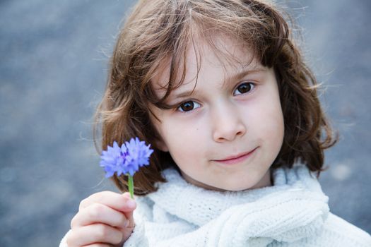 Little girl holding a wild flower in her hand