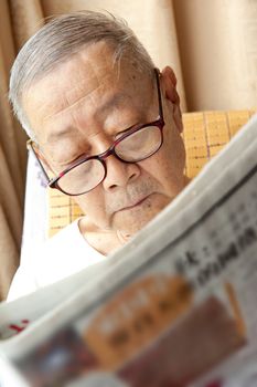 a senior man is reading newspaper