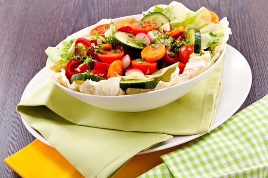 fresh mixed colorful salad on wooden table with green and yellow decoration