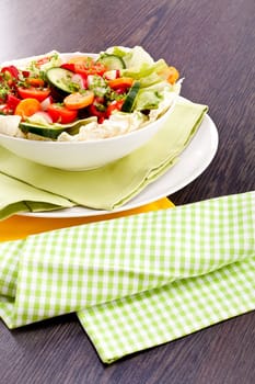 fresh mixed colorful salad on wooden table with green and yellow decoration