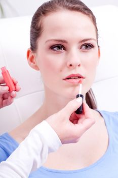 brunette attractive woman portrait applying lipstick lipgloss in beauty salon