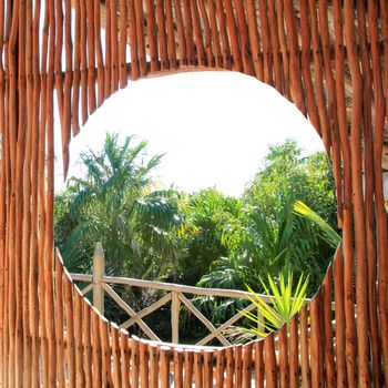 circle window in wooden sticks cabin with tropical Jungle background