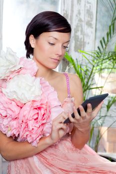 fashion woman and tablet ebook reading at home with spring pink flowers dress