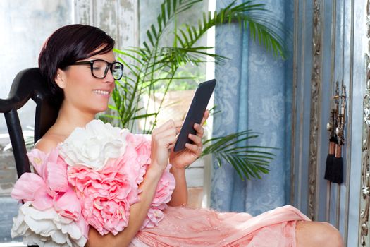 fashion woman and tablet ebook reading at home with spring pink flowers dress