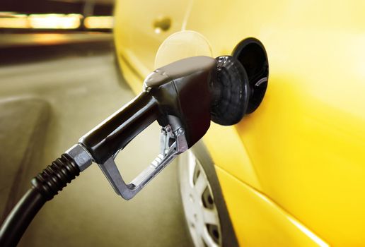 yellow car at gas station being filled with fuel